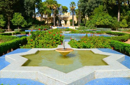 Jardin Jnan Sbil in Fes, a tranquil spot for things to do in Fes, with shaded pathways, a central fountain with intricate tilework, and vibrant flowerbeds, a top Fes Morocco attraction near the medina.